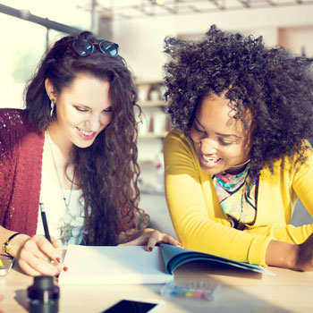 Two college-age girls reading a book